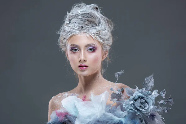 Winter Beauty Mujer con ropa hecha de flores congeladas cubiertas de escarcha, con nieve en la cara y los hombros. Maquillaje de chica de Navidad. Maquillaje de la Reina de la nieve. Aislado sobre un fondo gris. — Foto de Stock