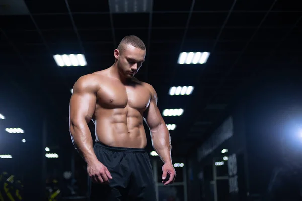 Deportista muscular sexy está de pie en un gimnasio relajante antes del entrenamiento —  Fotos de Stock