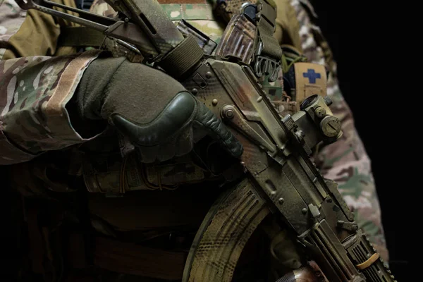Zbliżenie nowoczesnego karabinu maszynowego w rękach wojskowego ubranego w kamuflaż i pełny sprzęt, odizolowanego na czarnym tle — Zdjęcie stockowe