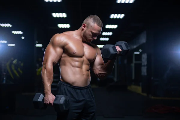 Culturista adulto joven haciendo levantamiento de pesas en el gimnasio. —  Fotos de Stock