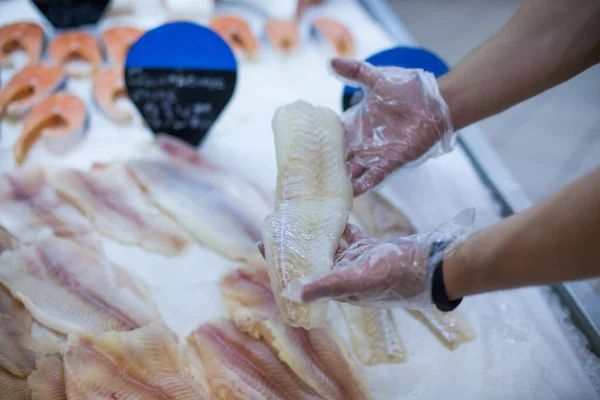 Primer plano de mans manos guantes sosteniendo pescado congelado elegir alimentos en una tienda de comestibles — Foto de Stock
