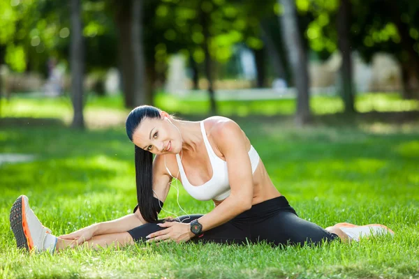 Mulher esporte bonita fazendo alongamento exercício de fitness no parque da cidade em grama verde. Posturas de ioga — Fotografia de Stock