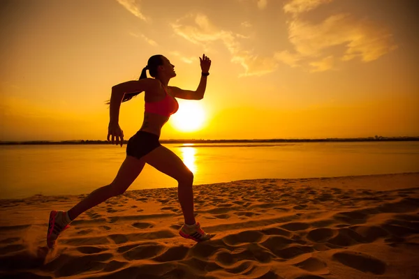 Kvinnan kör ensam på vacker solnedgång på stranden. Sommar sport och frihet koncept. — Stockfoto