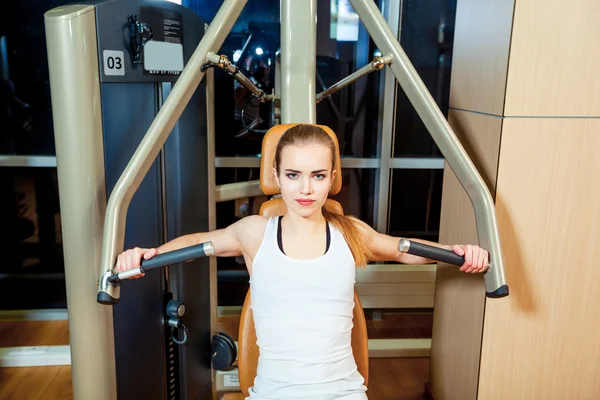 Esporte, fitness, estilo de vida e conceito de pessoas - jovem mulher flexionando músculos na máquina de ginásio — Fotografia de Stock