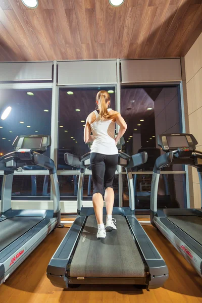 Chica bonita haciendo ejercicio en una cinta de correr en el gimnasio y sonriendo — Foto de Stock