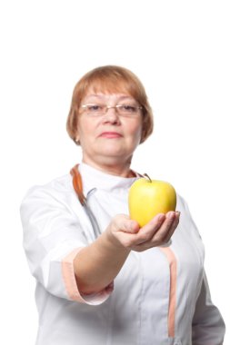 Doktor kadın steteskopla gülümsüyor. Elinde taze elma var. Beyaz arkaplan üzerinde izole edilmiş