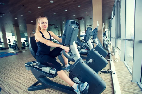 Hermosa chica haciendo ciclismo indoor en un club de fitness —  Fotos de Stock