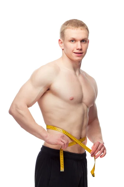 Hombre en forma midiendo su cintura después de un entrenamiento en el gimnasio, fondo blanco aislado — Foto de Stock