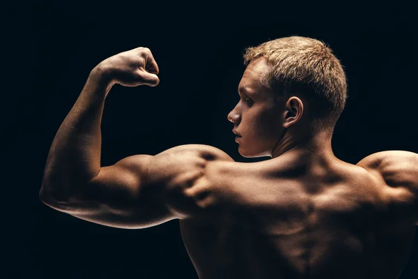 Nahaufnahme von Sportlern muskulös isoliert auf schwarzem Hintergrund — Stockfoto