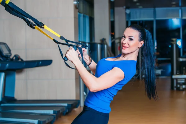 Young attractive woman training with htrx fitness straps in the gyms studio — Stock Photo, Image
