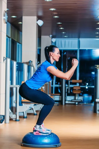 Mujer haciendo sentadillas en entrenador de equilibrio — Foto de Stock