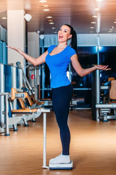 Happy Woman smiling on weighing scales at gym — Stock Photo, Image