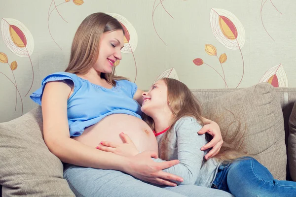 Happy kid girl hugging pregnant mothers belly — Stock Photo, Image