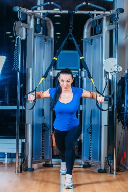 Gülümseyen genç kadın spor salonunda egzersiz yaparak Trx. fitness, spor, egzersiz, teknoloji ve insan kavramlar-.
