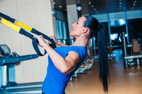TRX. fitness, sport, ćwiczenia, technologia i ludzie pojęcia - uśmiechnięta młoda kobieta robi ćwiczenia na siłowni. — Zdjęcie stockowe