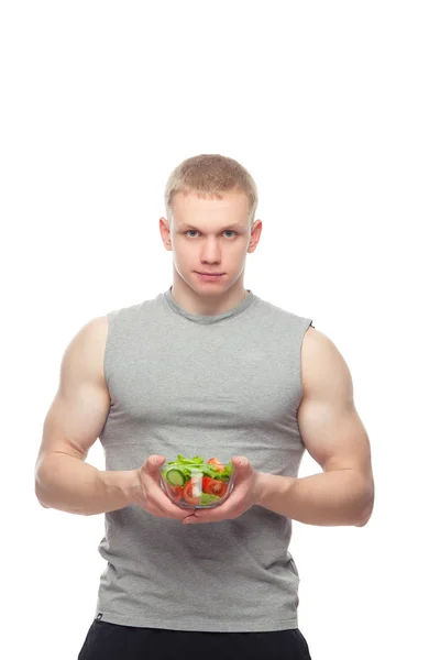 Joven hombre musculoso feliz comiendo una ensalada sobre fondo blanco . — Foto de Stock