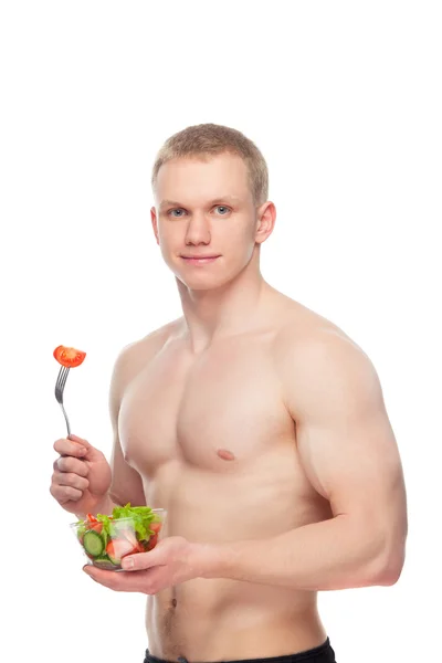 Jonge gelukkig gespierde man een salade eten op witte achtergrond. — Stockfoto