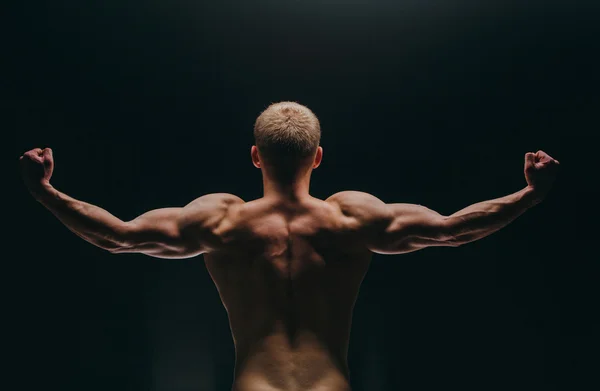 Muskulös ung man visar hans biceps isolerad på svart bakgrund. — Stockfoto