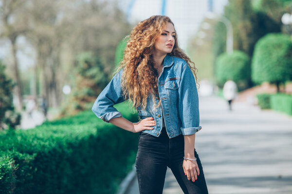 Beautiful young Caucasian girl with curly hair outdoors