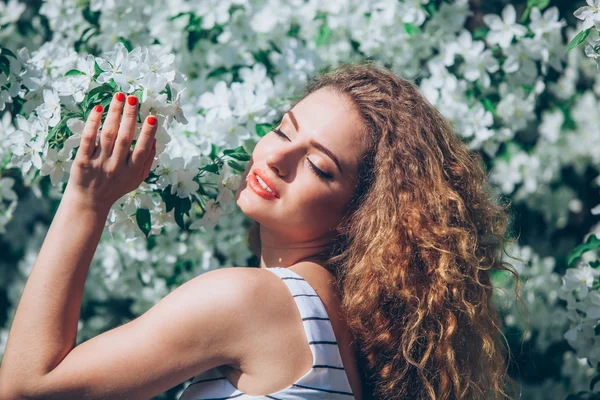 Wanita muda yang cantik dengan rambut keriting yang indah di luar, berbunga — Stok Foto