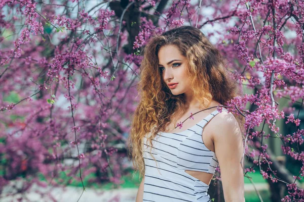 Wanita muda yang cantik dengan rambut keriting yang indah di luar, berbunga — Stok Foto