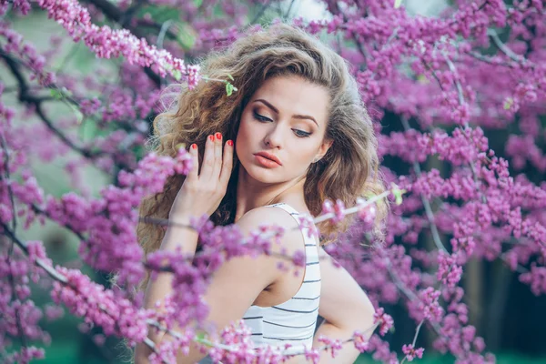 Wanita muda yang cantik dengan rambut keriting yang indah di luar, berbunga — Stok Foto