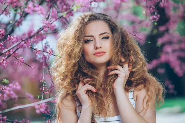 Beautiful young woman with gorgeous curly fair outdoors,flowering — Stock Photo, Image