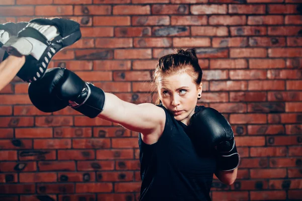 Woman wearing boxing gloves hitting training mits man is holding — Stock Photo, Image