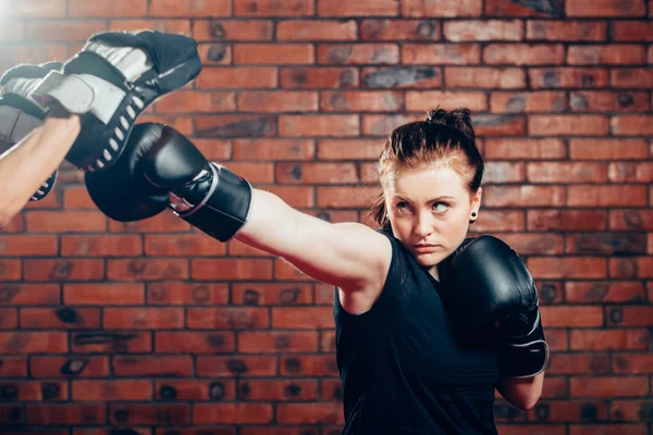 Mujer usando guantes de boxeo golpeando entrenamiento mits hombre está sosteniendo —  Fotos de Stock