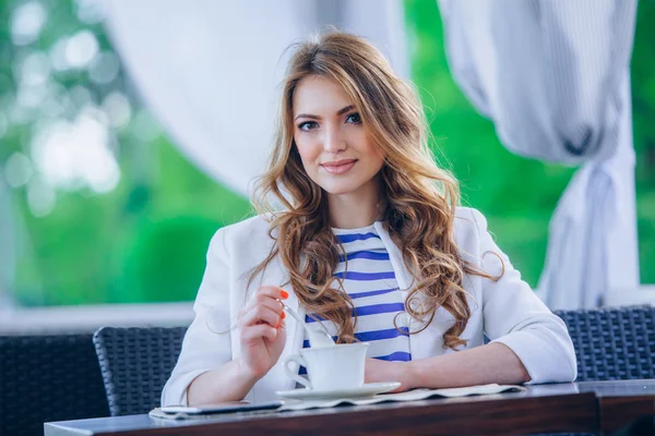 Hermosa joven en la cafetería al aire libre leyendo un libro y beber café. teléfono. Estudiante. mujer de negocios — Foto de Stock