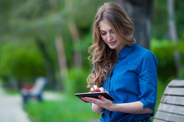 공원 벤치에 태블릿 컴퓨터를 사용 하 여 젊은 여자의 모습 — 스톡 사진