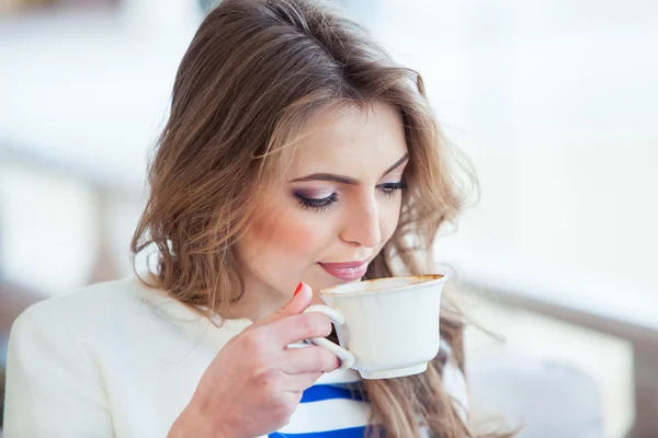 Hermosa joven en la cafetería al aire libre leyendo un libro y beber café. teléfono. Estudiante. mujer de negocios — Foto de Stock