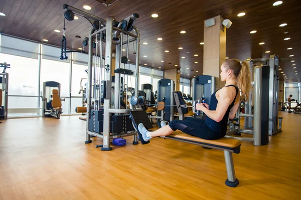 スポーツ、フィットネス、ライフ スタイル、人々 の概念 - 若い女性のジムのマシンで筋肉を屈曲 — ストック写真
