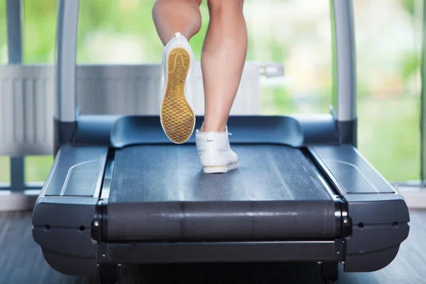 Fitness-Mädchen läuft auf Laufband. Frau mit muskulösen Beinen im Fitnessstudio — Stockfoto