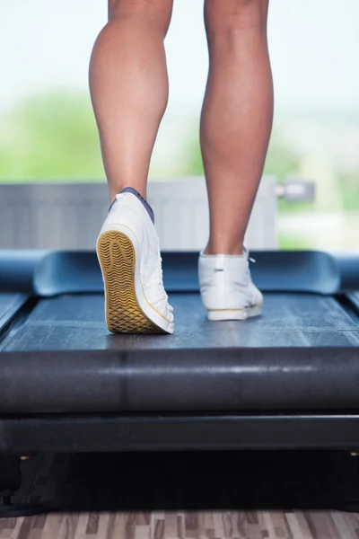 Fitness flicka som springer på löpband. Kvinna med muskulösa ben i gymmet — Stockfoto