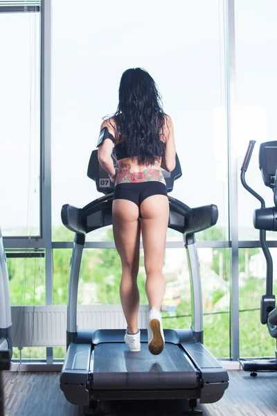 Rear view of female running on treadmill in gym — Stock Photo, Image