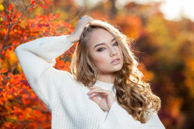 güzel genç kadın kıvırcık saçlı bir arka plan kırmızı ve sarı sonbahar yaprakları
