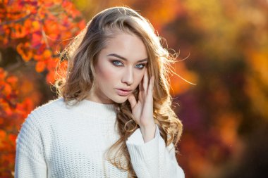 güzel genç kadın kıvırcık saçlı bir arka plan kırmızı ve sarı sonbahar yaprakları