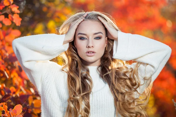 Hermosa joven con el pelo rizado sobre un fondo de hojas de otoño rojas y amarillas — Foto de Stock