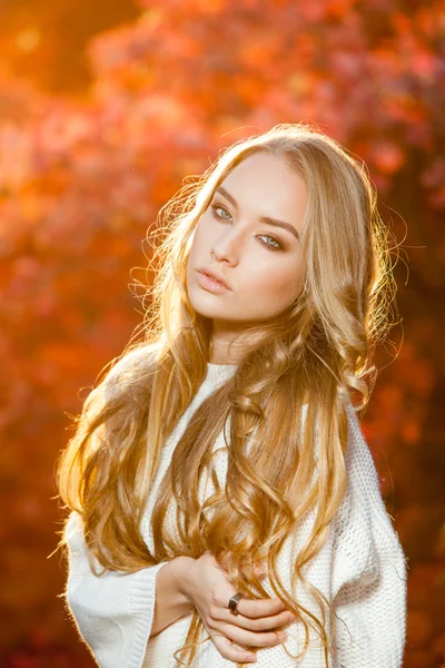 Mujer joven sobre un fondo de hojas de otoño rojas y amarillas con hermoso pelo rizado — Foto de Stock