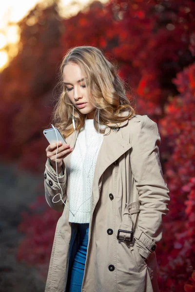 Jeune femme beauté écrivant un message sur un téléphone portable dans un parc d'automne — Photo