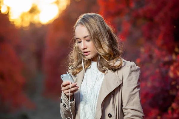 Jovem mulher de beleza escrevendo mensagem no celular em um parque de outono — Fotografia de Stock