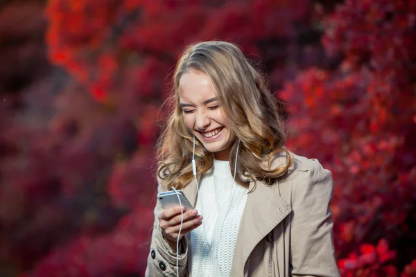 Junge Schönheit schreibt Nachricht auf Handy in einem herbstlichen Park — Stockfoto