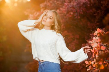 güzel kıvırcık saçlı genç kadın bir arka plan kırmızı ve sarı sonbahar yaprakları