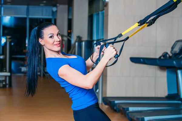 Young attractive woman training with htrx fitness straps in the — Stock Photo, Image