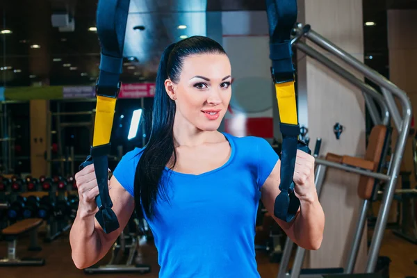 Young attractive woman training with htrx fitness straps in the — Stock Photo, Image