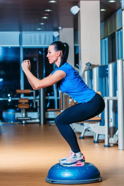 Mujer haciendo sentadillas en entrenador de equilibrio — Foto de Stock