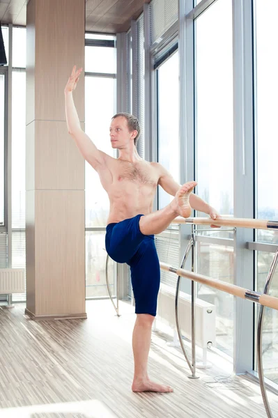 In the hall man doing stretching near Barre. — Stock Photo, Image