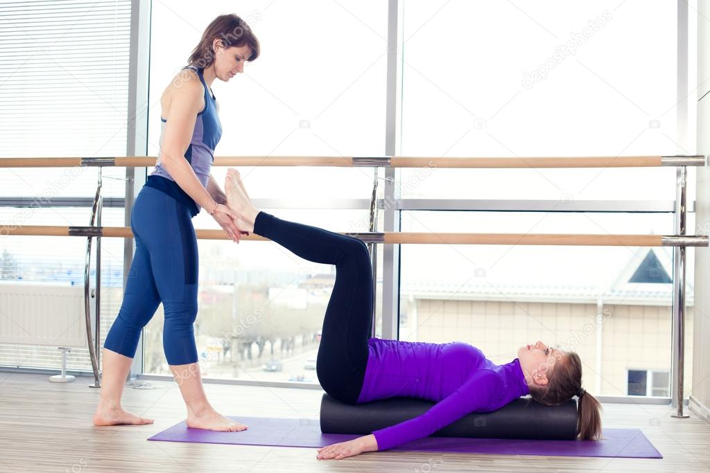Aerobics Pilates personal trainer helping women group in a gym c
