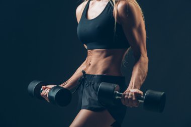 koyu arka plan üzerinde dumbbells ile atletik kadın